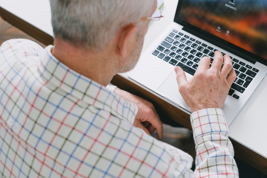 Starszy mężczyzna wypełnia wniosek ETA bez smartfona na laptopie w domu